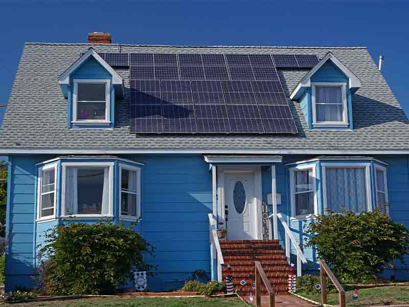 small blue two story home with solar panels on roof