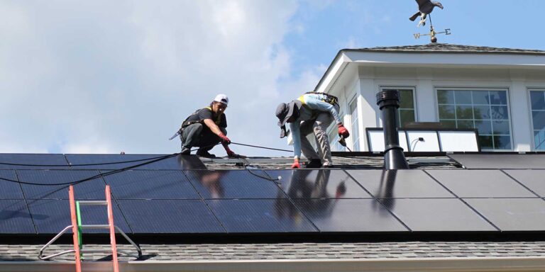 professional installers on roof of a home installing solar panels